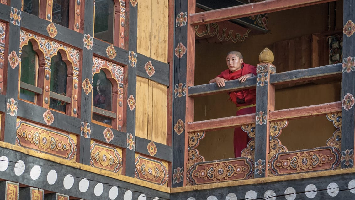 En ung munk holder øje fra en balkon i Paro Dzong